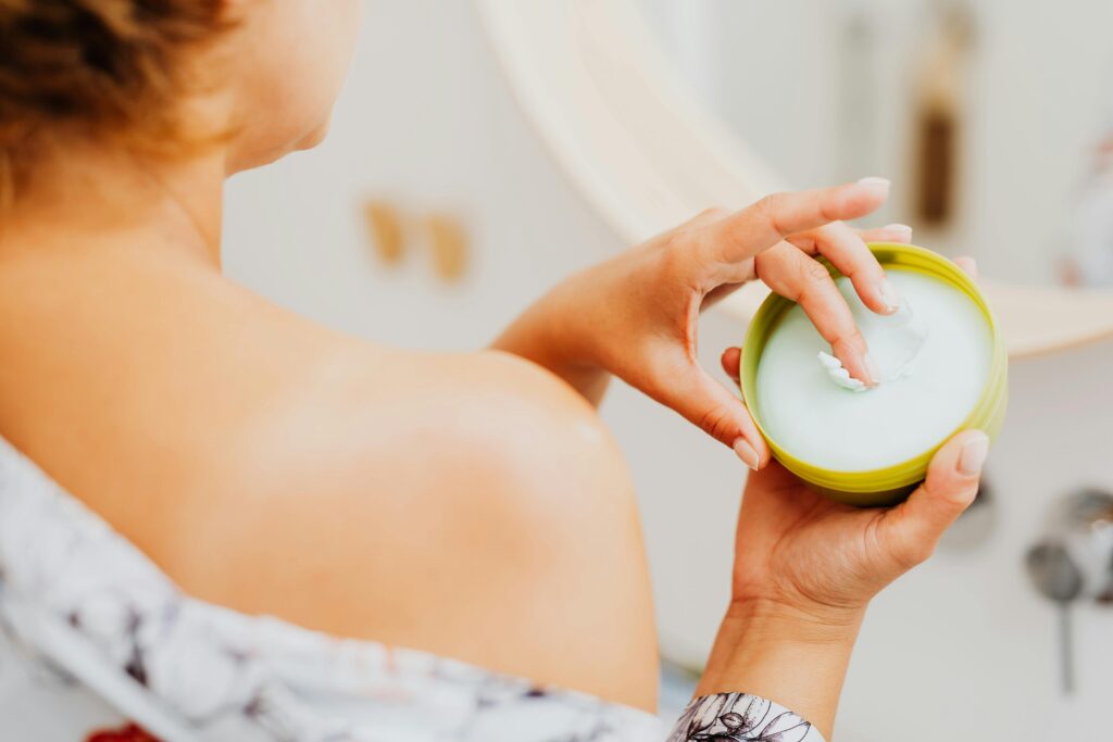 Close-up of a woman applying cream to her skin, emphasizing personal care and wellness.